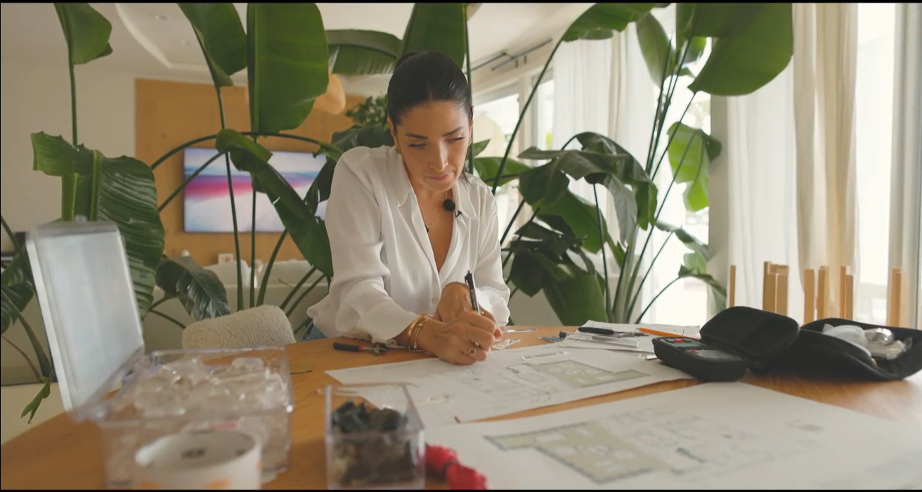 Esteffany evaluating stone samples using a pendulum inside a materials showroom.